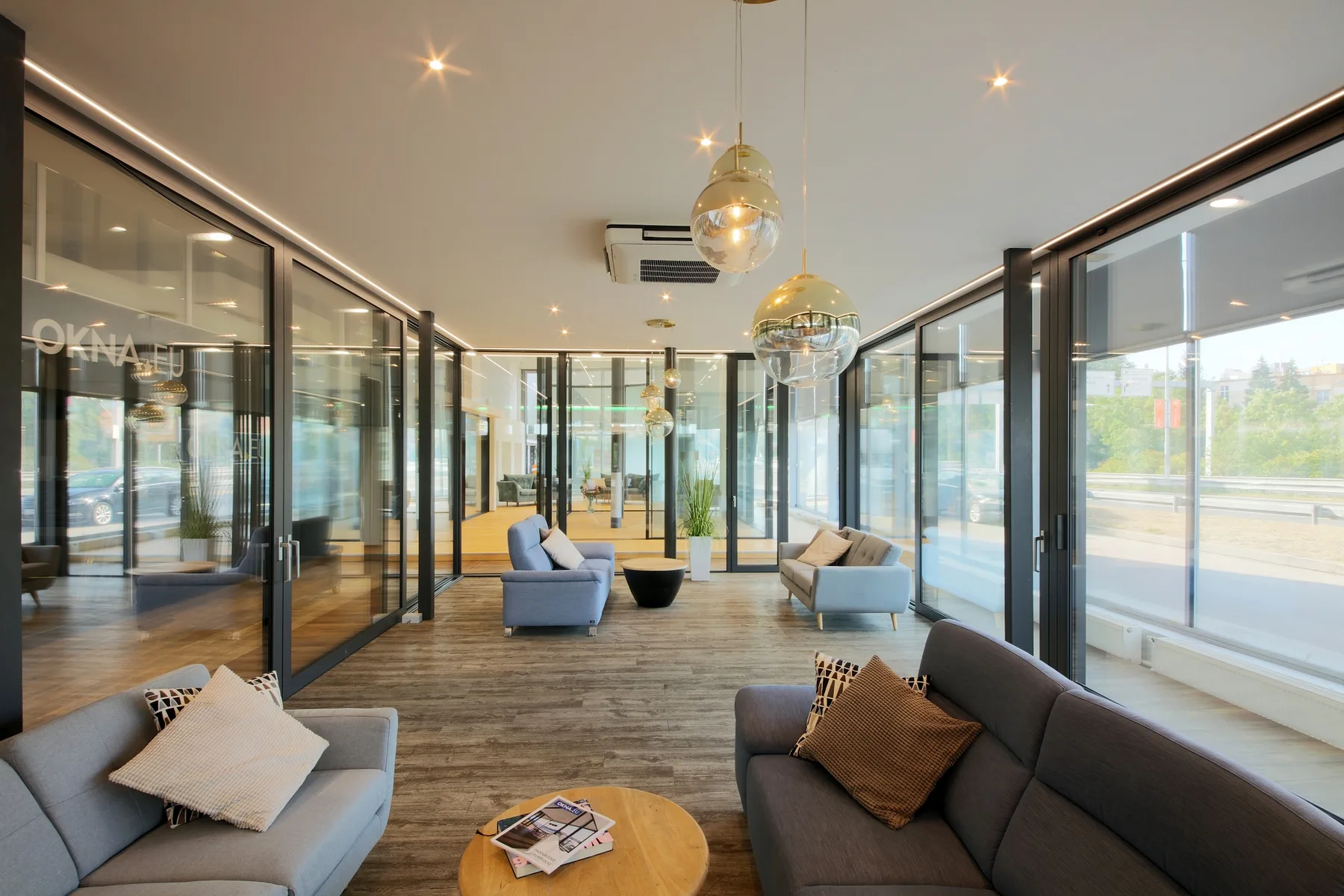 Prémiový showroom OKNA.EU Praha Pankrác — lounge s prosklenými stěnami a mosaznými svítidly